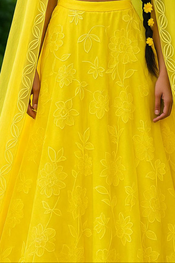Woman in a yellow traditional outfit with a green leafy background
